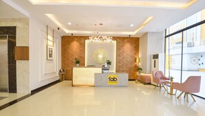 A hotel reception area with a modern design, featuring a reception desk, seating area, and large windows offering views of the city. - FabHotel Prime Spectrum Metro - With Pool | 5 mins Walk from Sector 75 Metro (Noida)