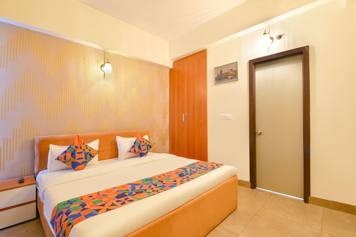 A hotel room with a large bed, a wooden wardrobe, and a door.