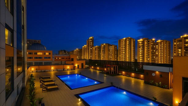 A rooftop pool area with two pools, lounge chairs, and a cityscape view at dusk. - FabHotel Prime Spectrum Metro - With Pool | 5 mins Walk from Sector 75 Metro (Noida)