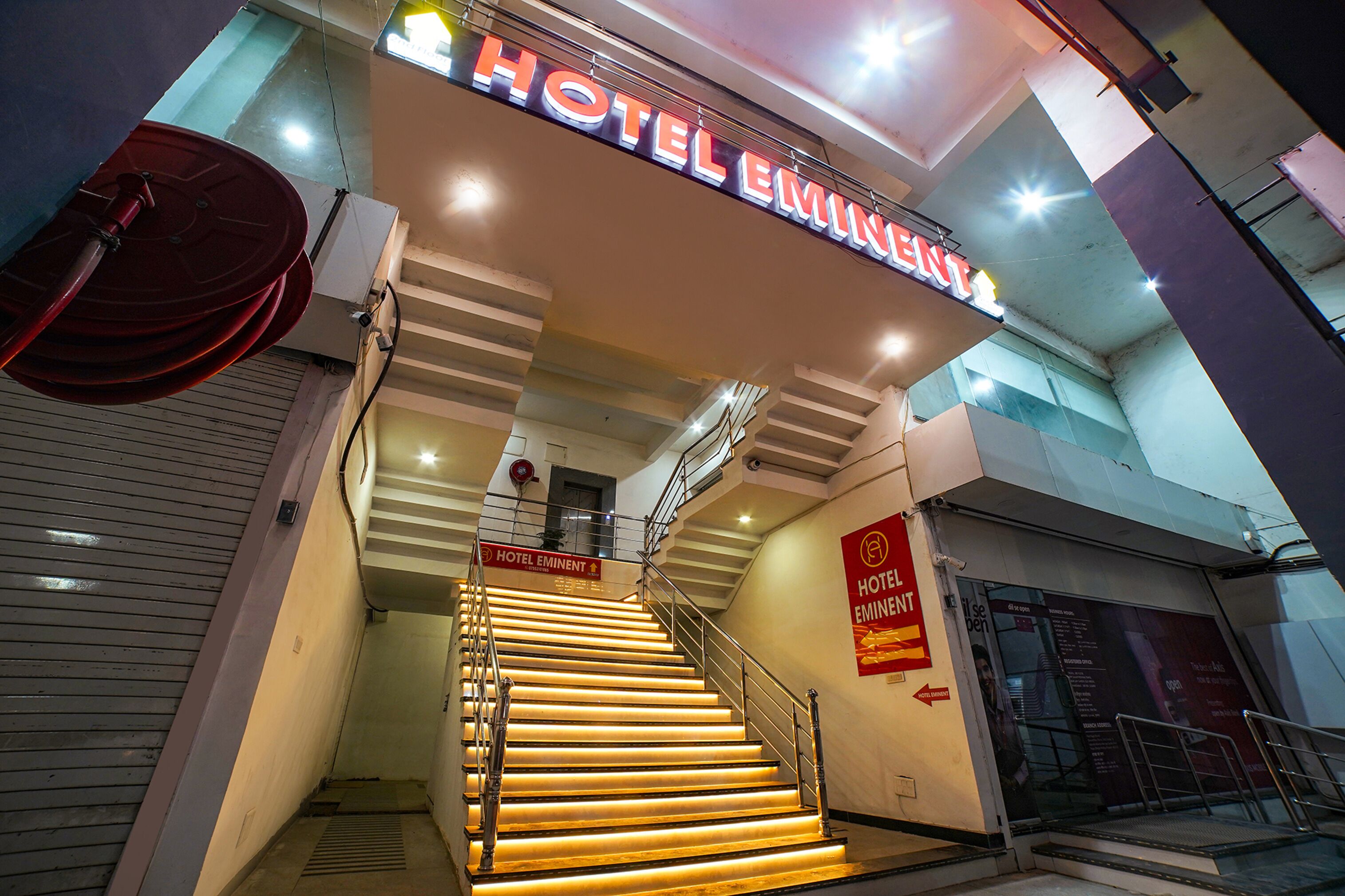 Een hotelingang met een trap die naar de receptie leidt, verlicht door hangende lampen.