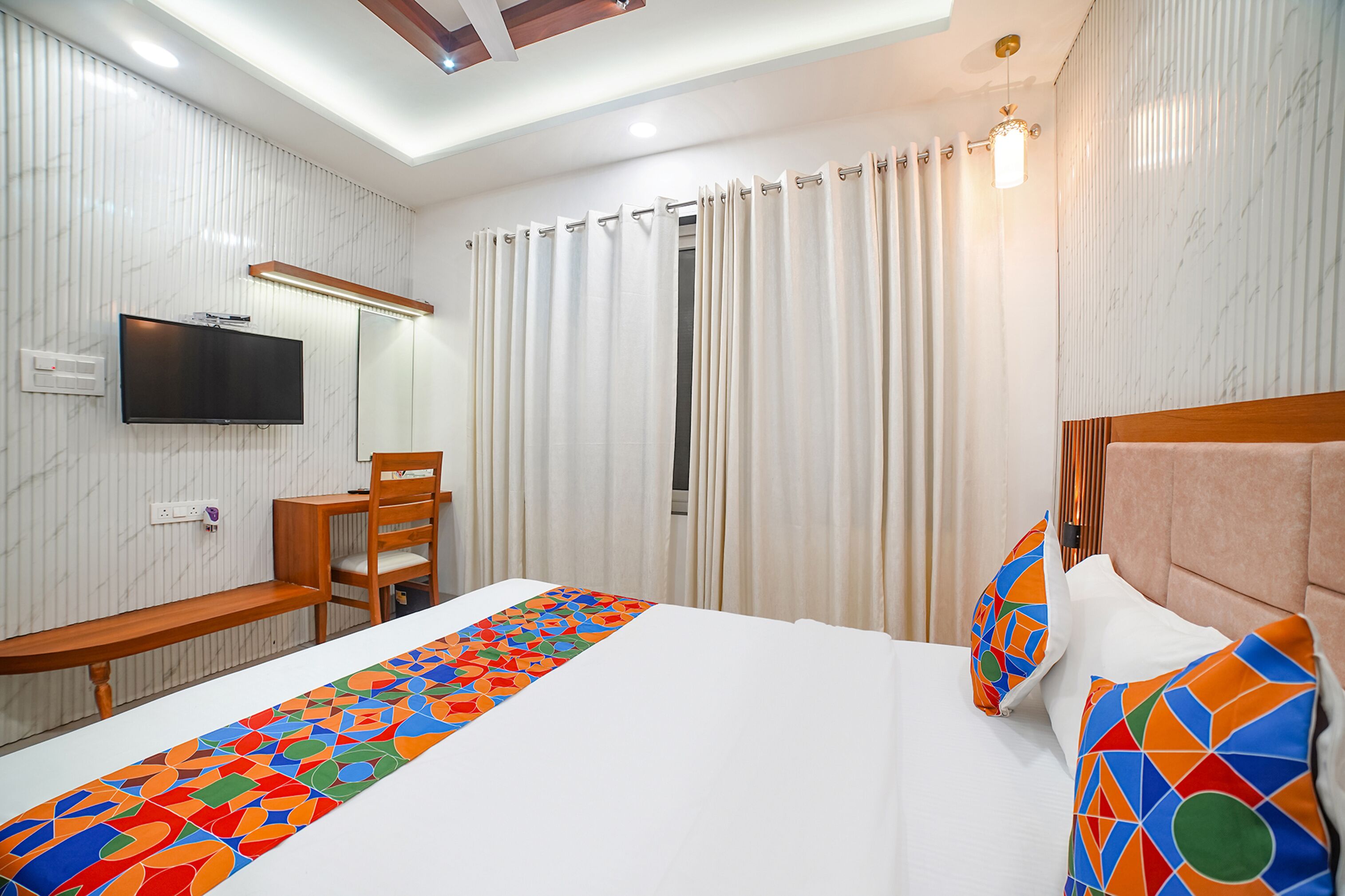 Ein Hotelzimmer mit Bett, Fernseher, Schreibtisch und Stuhl.