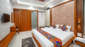 A modern bedroom with a large bed, wooden wardrobe, and a television on the wall. - Fabhotel Eminent (Bhopal)