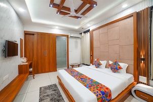 A modern bedroom with a large bed, wooden wardrobe, and a television on the wall.