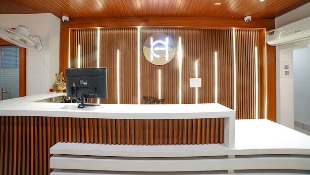 A reception desk with a modern design, featuring a wooden panel backdrop and a central logo. - Fabhotel Eminent (Bhopal)