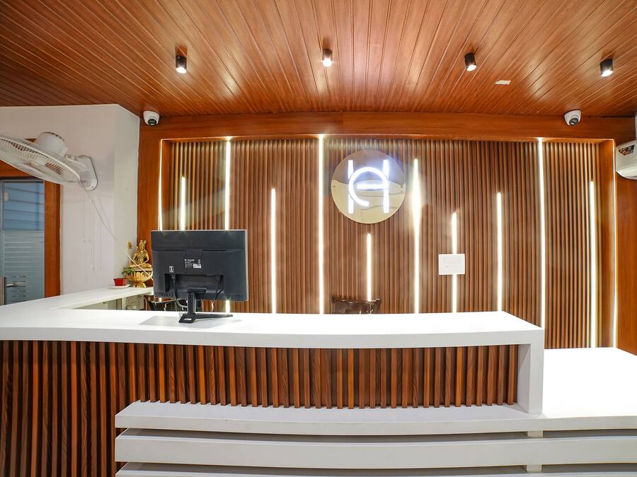 Un mostrador de recepción de diseño moderno, con un panel de madera en el fondo y un logotipo central.