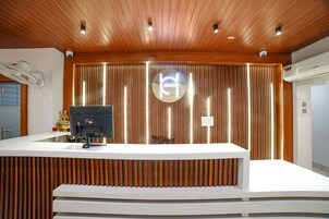 A reception desk with a modern design, featuring a wooden panel backdrop and a central logo.