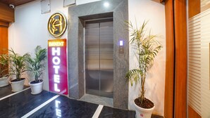 An elevator with a modern design, a prominent hotel sign, and potted plants near the entrance. - Fabhotel Eminent (Bhopal)