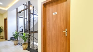 A hotel lobby with a wooden door labeled 204, a staircase, and two potted plants. - Fabhotel Weekend (Indore)
