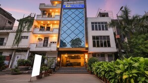 A modern building with a prominent 'fabHOTELS' sign, featuring a glass facade and a balcony on the upper floor.