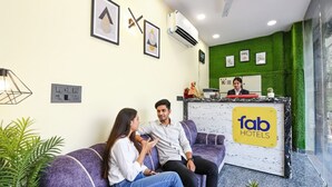 A reception area with a reception desk labeled "fab hotels," a purple sofa, and a small table with a plant.