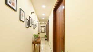 A hallway with framed pictures on the wall, a wooden table with potted plants, and a wooden door.