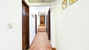 A corridor with wooden doors, tiled flooring, and framed pictures on the walls. - Via Krishna Residency - Nr. Nehru Place Metro (New Delhi)