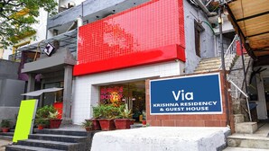 A building with a red awning, a sign for 'Via Krishna Residency & Guest House,' and steps leading to the entrance. - Via Krishna Residency - Nr. Nehru Place Metro (New Delhi)