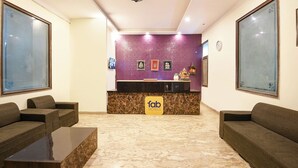 Ein Hotel-Empfangsbereich mit Marmorboden, Sofas, einem Empfangstresen und gerahmten Bildern an der Wand.