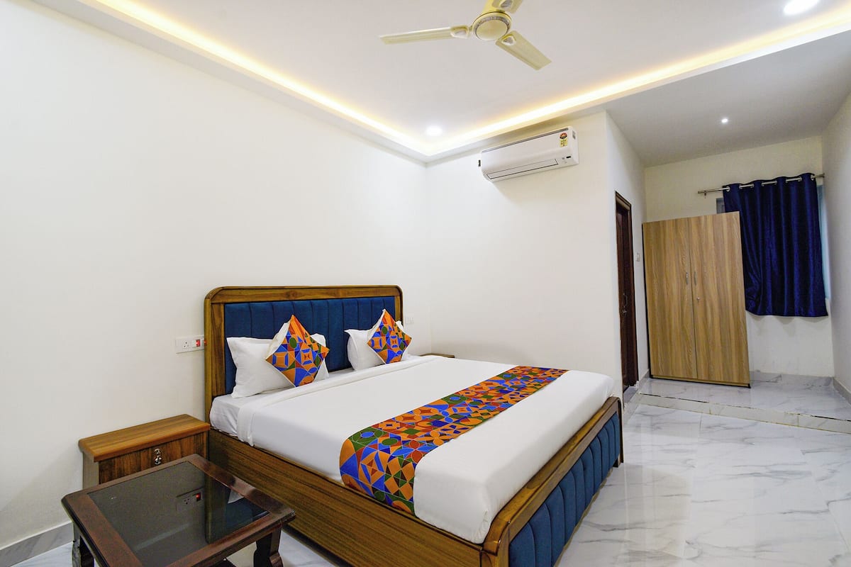 A hotel room with a bed, bedside table, and an air conditioning unit.