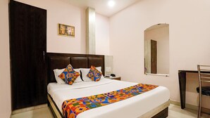 Quarto de hotel com uma cama grande, uma mesa de cabeceira, um espelho e uma porta.