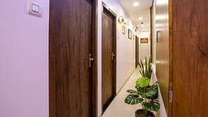 Um corredor com portas de madeira, um vaso de planta e um aparelho de iluminação.