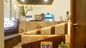 A hotel reception area with a marble counter, a seating area with a tufted sofa, and a Pepsi refrigerator. - FabHotel Malali Residency (Mumbai)