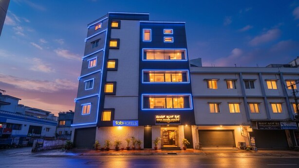 A multi-story hotel with a modern facade, illuminated windows, and a visible entrance with a sign. - FabHotel Classic Heights - Near Yelahanka Railway Station (Bangalore)