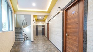 A hallway with a marble staircase, wooden doors, and a tiled floor. - FabHotel Classic Heights - Near Yelahanka Railway Station (Bangalore)