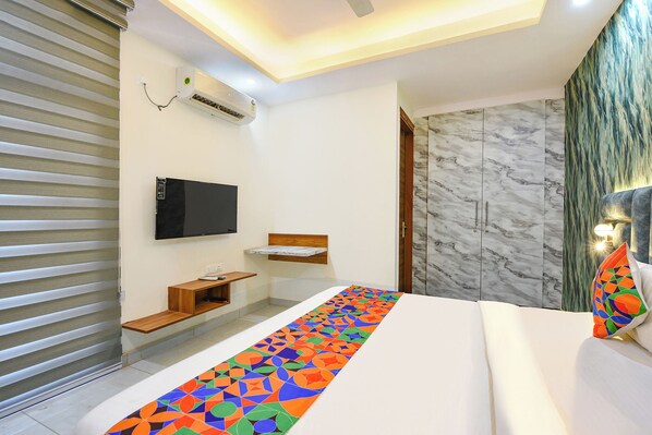 A modern hotel room with a bed, a TV, a wooden bench, a marble wall, and a patterned runner. - Fabhotel Sk Residency (Gurugram)