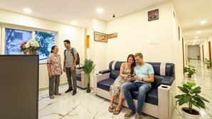 Ein Empfangsbereich mit Empfangstresen, einer Couch und einem Blumentopf.