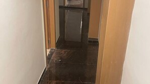 Un couloir étroit, doté d’un sol carrelé foncé et de portes en bois.