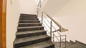 A staircase with a metal handrail and a wooden handrail on the right side. - Fabhotel Lloyd’S Inn (Chennai)