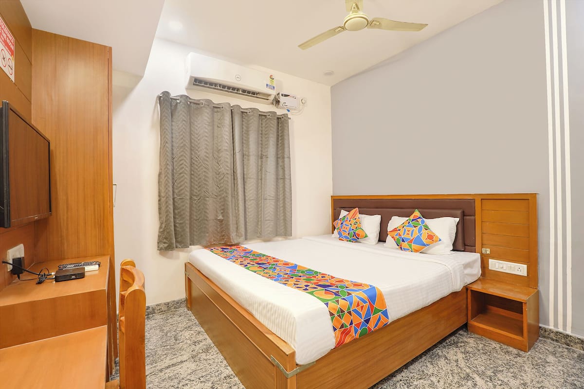 Un dormitorio con cama, escritorio, aire acondicionado y ventilador de techo.