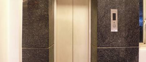 An elevator interior with a marble wall and a control panel.