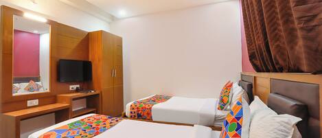 A hotel room with two beds, a desk, a television, and a ceiling fan.