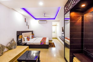 A modern hotel room with a bed, a desk, and a seating area.