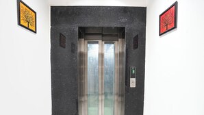 An elevator with a digital display showing the number 3, flanked by two framed artworks on the walls. - Fabhotel The Shivaay Palace (Varanasi)