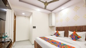 Habitación de hotel con cama, un banco de madera, ventilador de techo y una pared con diseños decorativos.