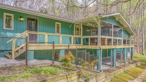 A two-story house with a covered porch, a fenced yard, and a wooden deck.