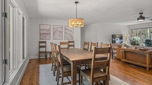 A dining area with a wooden table and chairs, a hanging light fixture, and artwork on the wall.