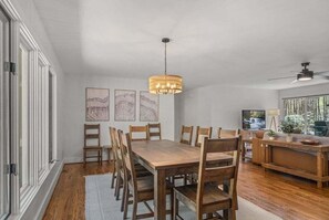 A dining area with a wooden table and chairs, a hanging light fixture, and artwork on the wall.