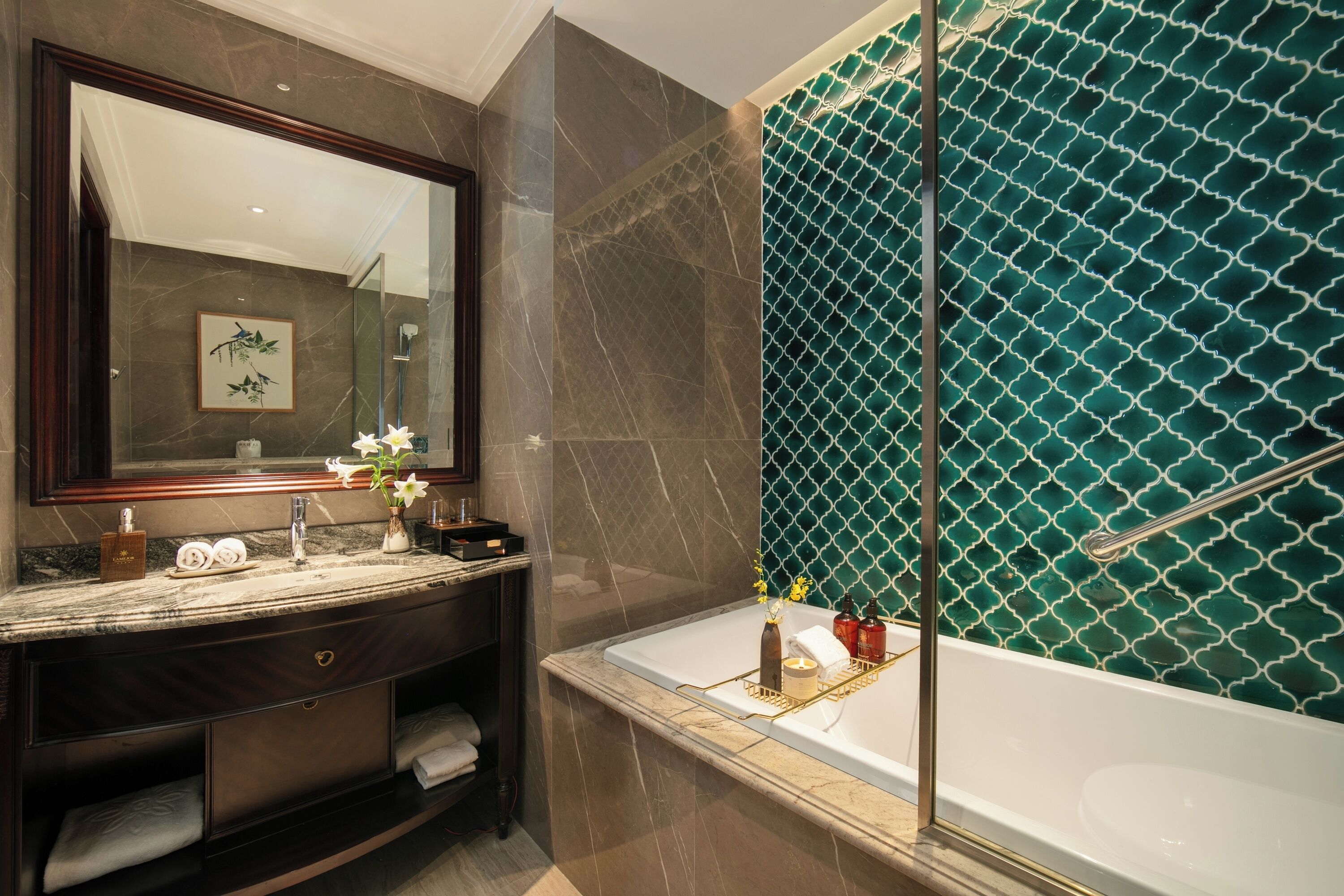A modern bathroom with a marble vanity, a large mirror, a bathtub, and a shower with a green patterned wall.