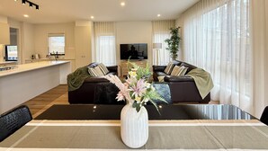Una sala de estar moderna con un conjunto de sofá, una mesa de comedor y una cocina al fondo.