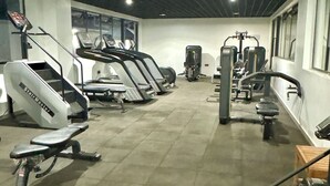 Une salle de sport équipée de tapis de course, d’appareils de musculation et d’un mur recouvert de miroirs.