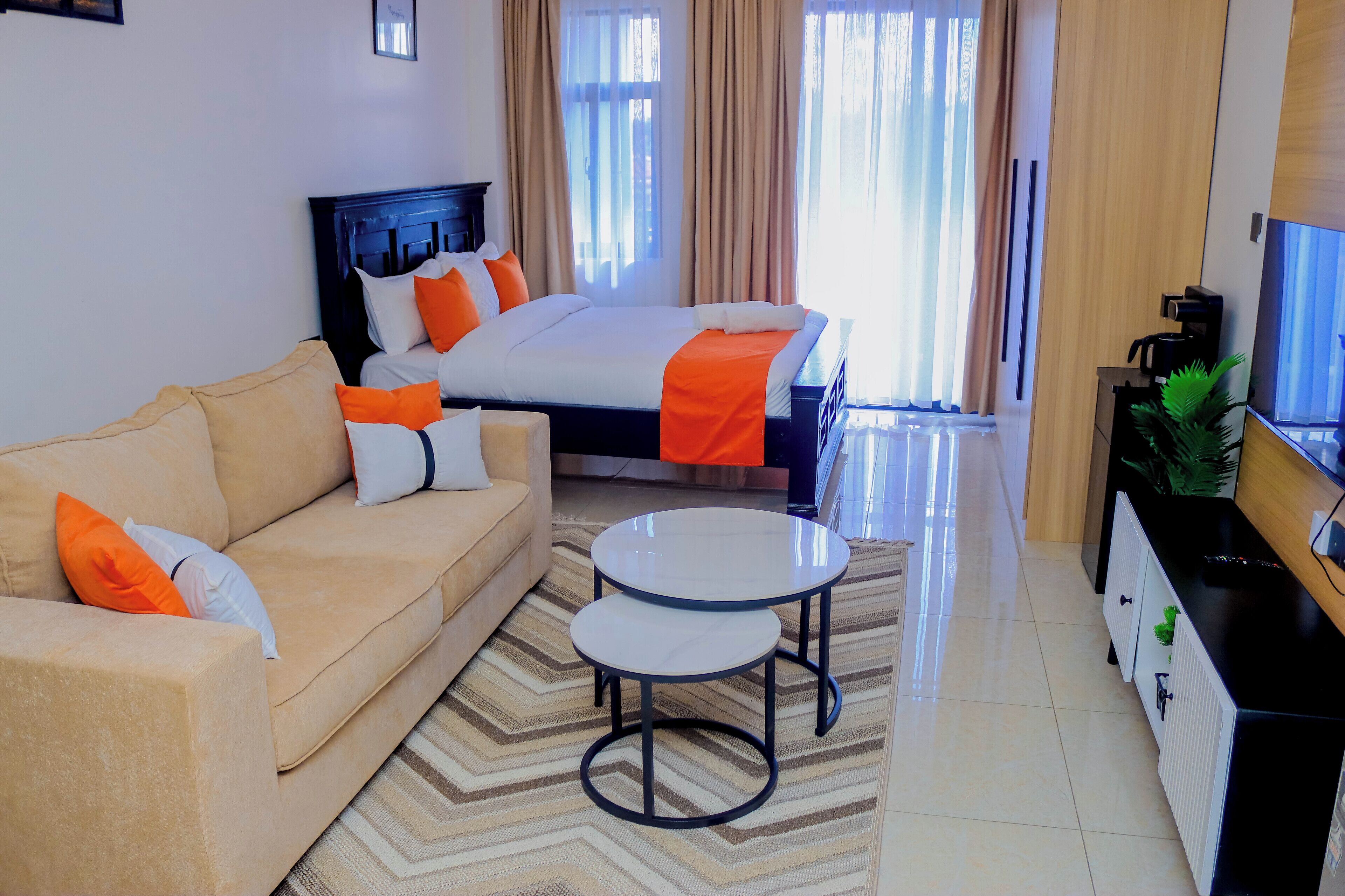 A hotel room with a bed, a sofa, a coffee machine, and a TV.