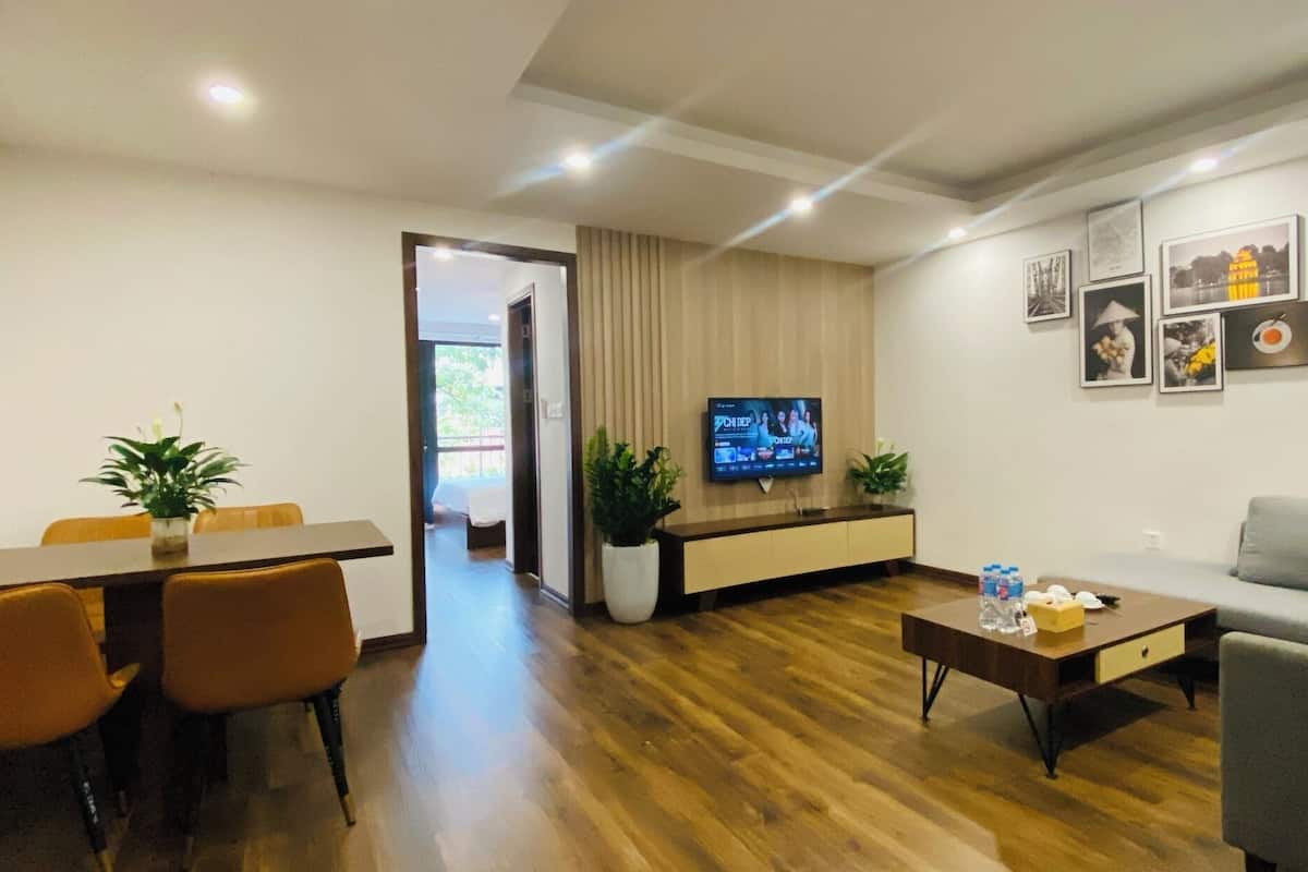 A modern living room with a TV, sofa, dining table, and chairs.