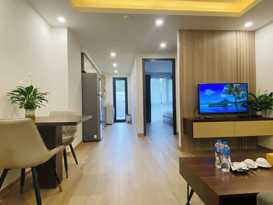 Une chambre d’hôtel moderne dotée d’un coin repas, d’une télévision et d’un couloir menant à un balcon.