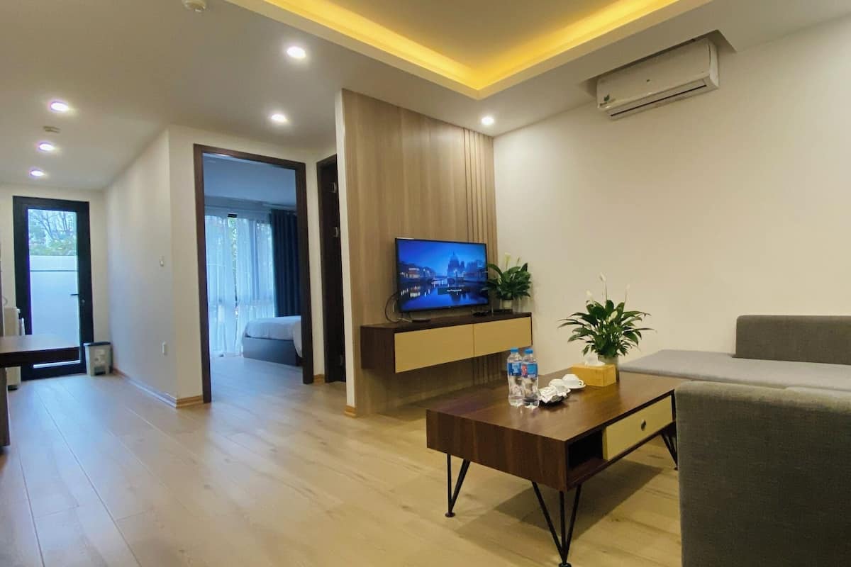 A modern living room with a sofa, a coffee table, a TV, and a plant.