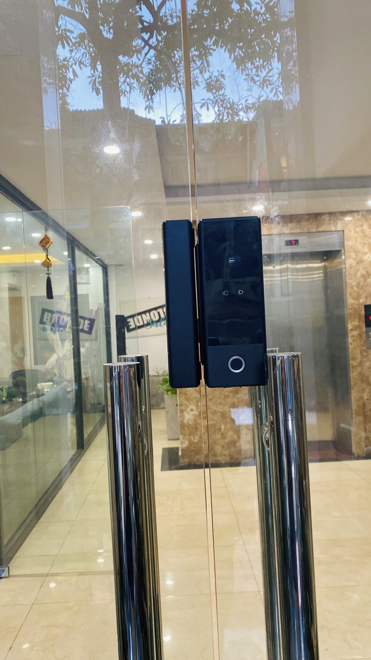 A glass door with a digital display and two metallic pillars.
