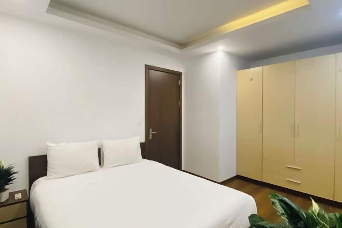 A hotel room with a bed, a wardrobe, a nightstand, and a potted plant.