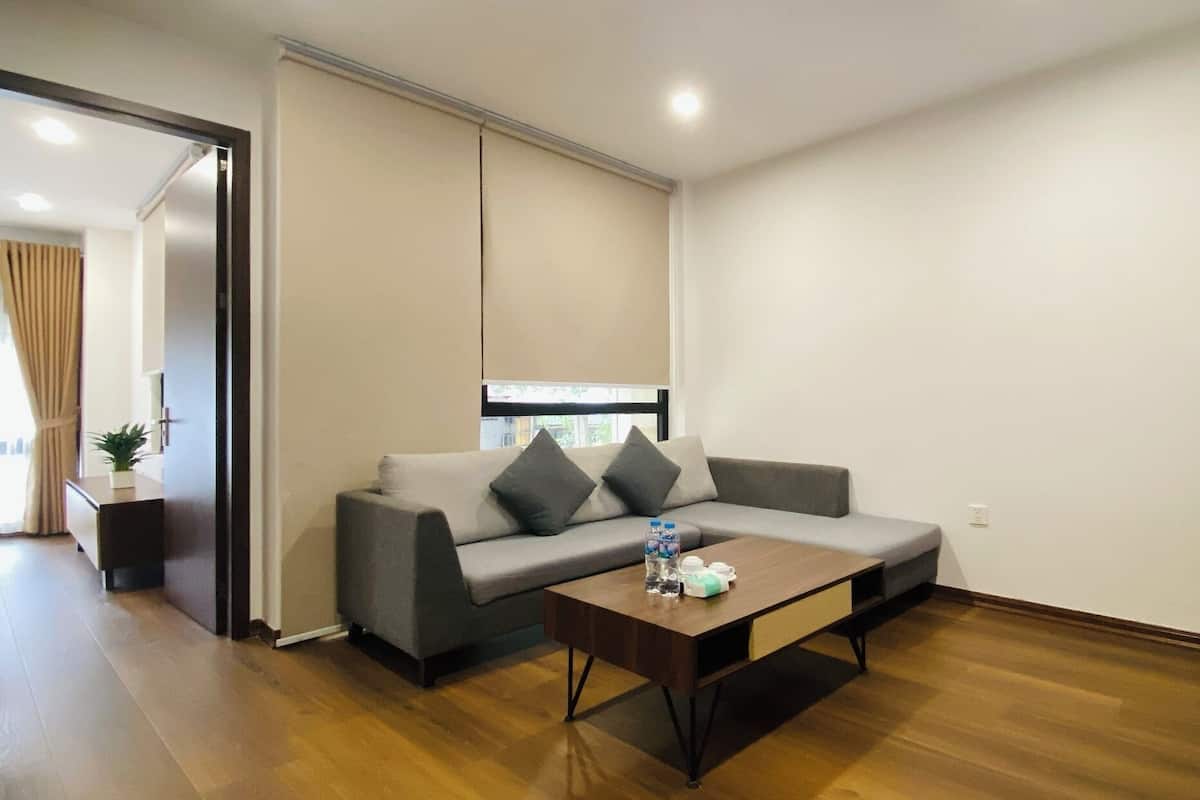 A modern living room with a grey sofa, a wooden coffee table, and a TV on a stand.