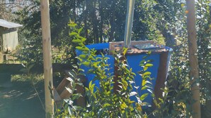 A rustic outdoor cooking setup with a blue container, wooden posts, and smoke rising from the top.