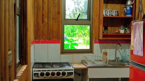 A compact kitchen with a gas stove, oven, and a window with a view of greenery.