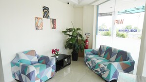 A hotel reception area with two patterned sofas, a small table, a potted plant, and artwork on the wall. - Hotel Shri Putiri (Pasir Gudang)